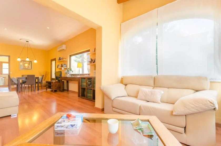 A bright living room with seating beside a dining area and glass coffee table.