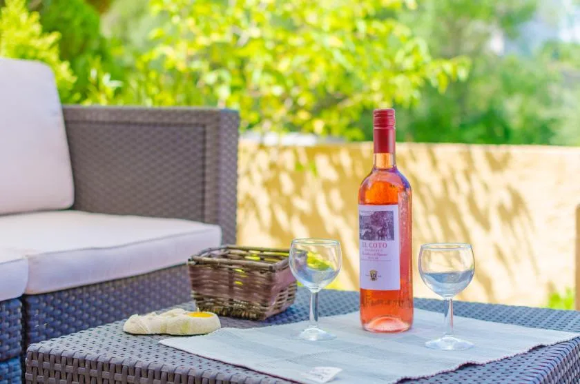 An outdoor patio seating area with wine and glasses on a table.