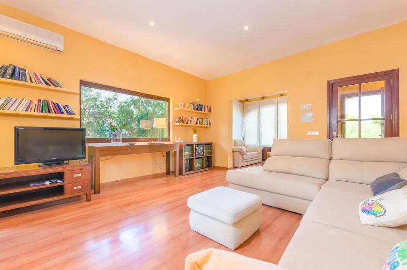 A bright living room with seating, a television, and a large window.