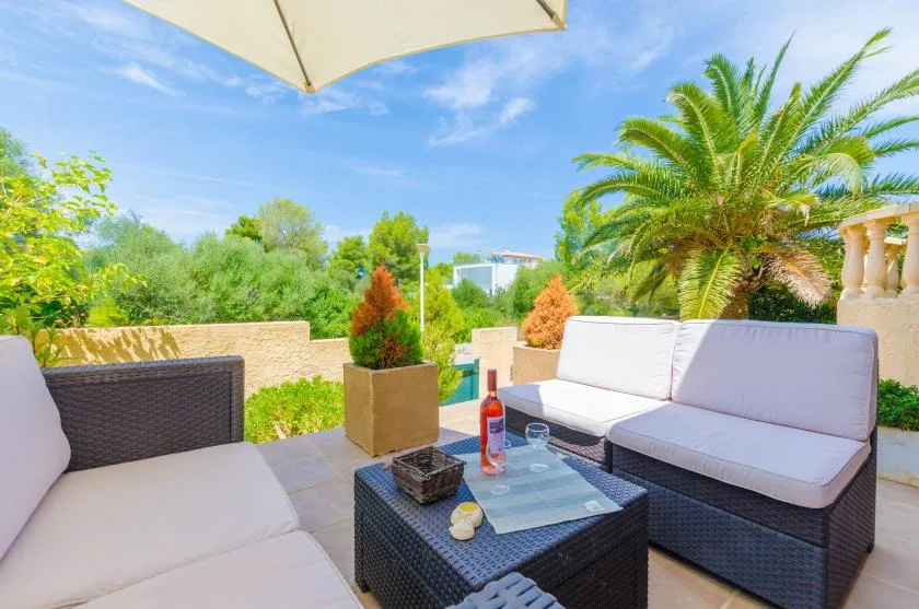 Outdoor patio seating surrounds a low table beneath a large umbrella.