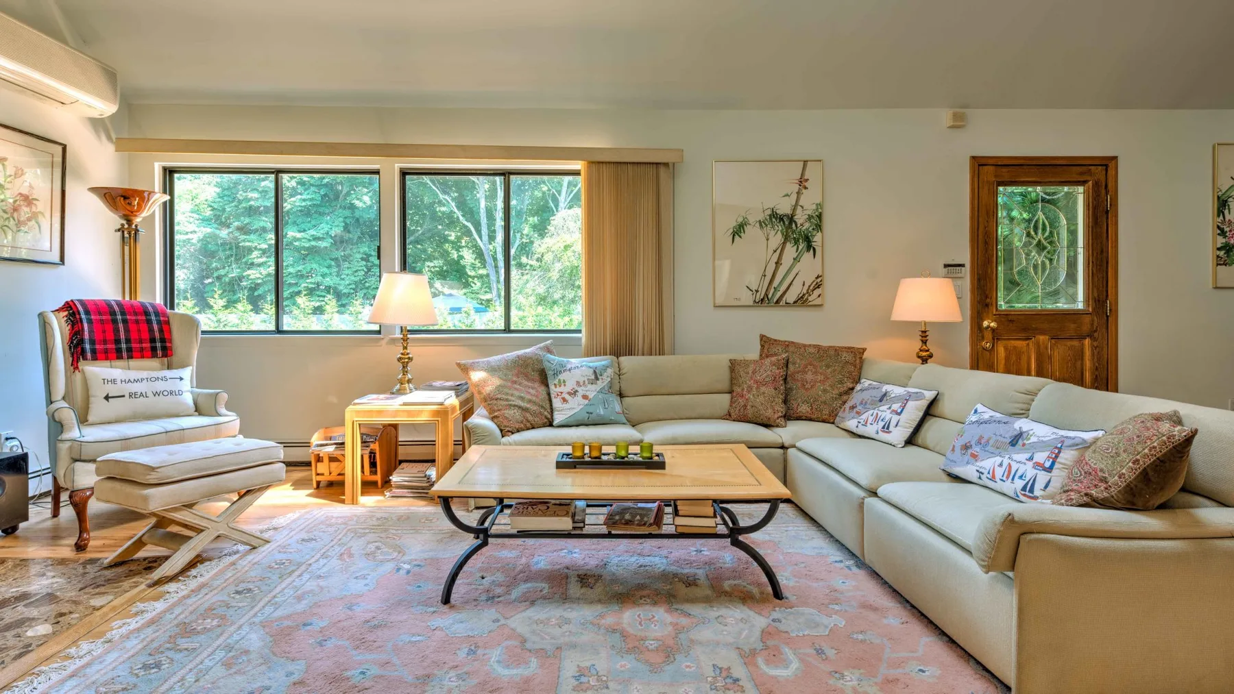A living room with seating around a coffee table beside large windows.