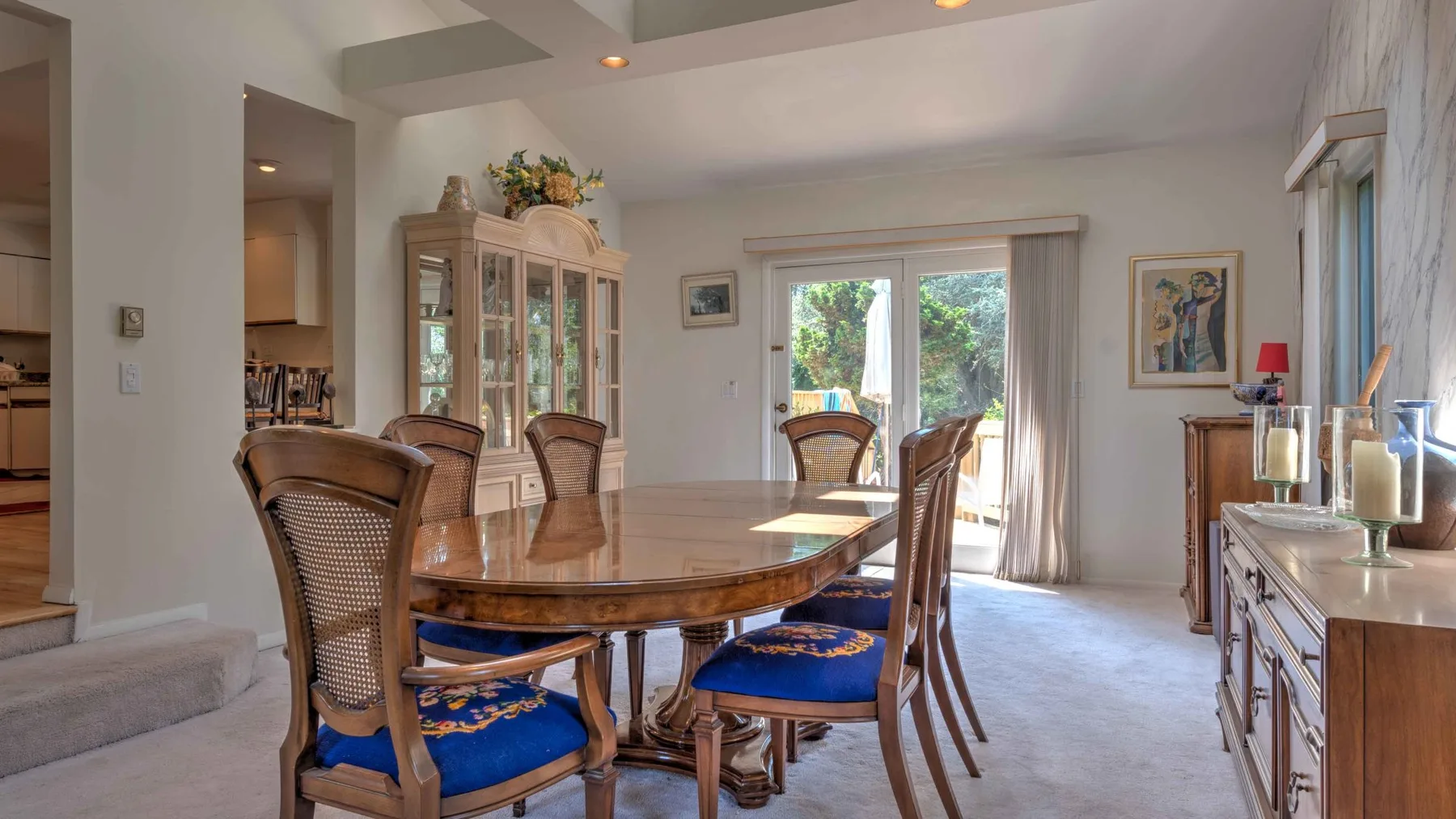 A dining room with a long wooden table and chairs beside a glass door.