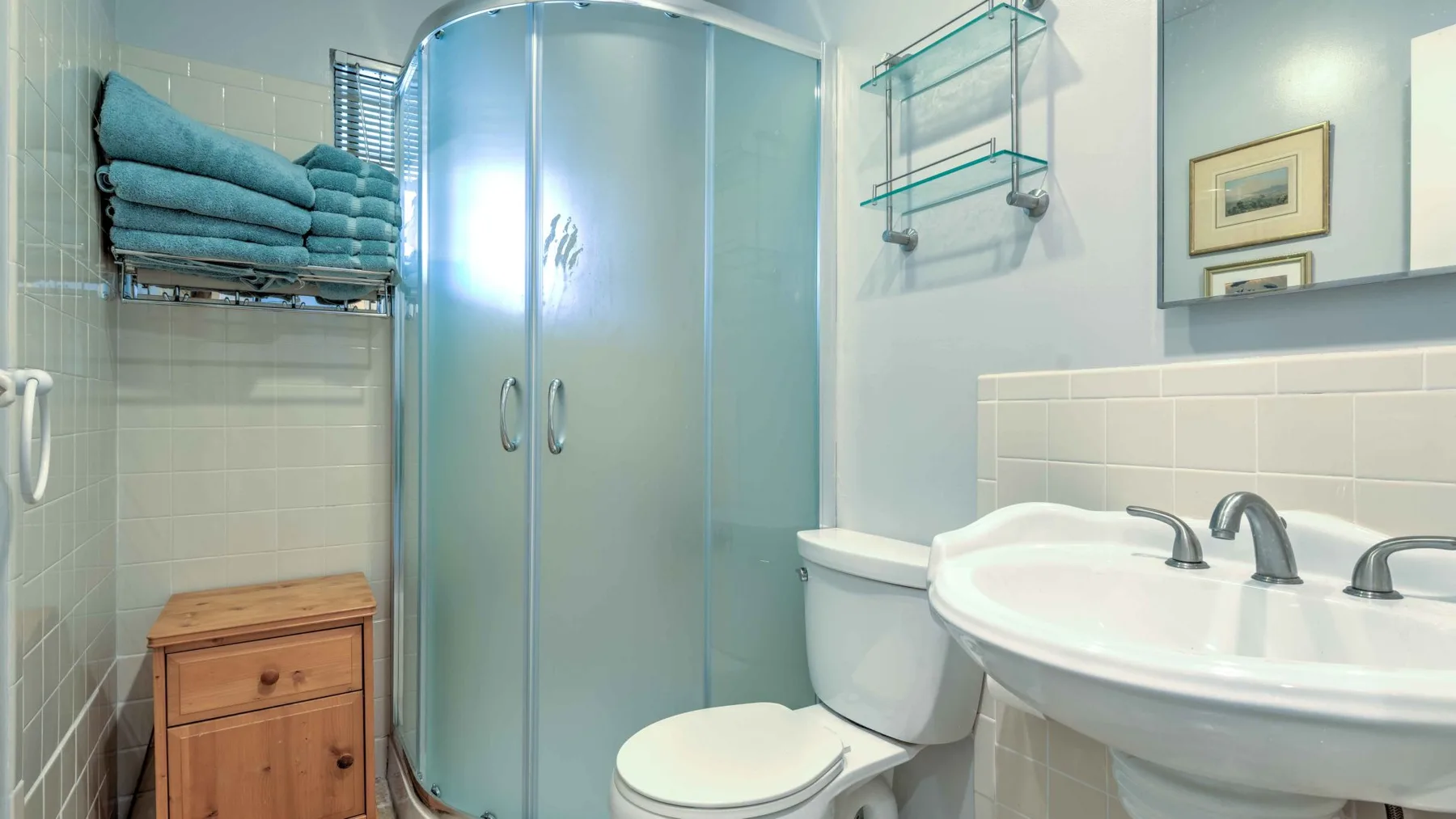 A bathroom with a curved glass shower and a sink.