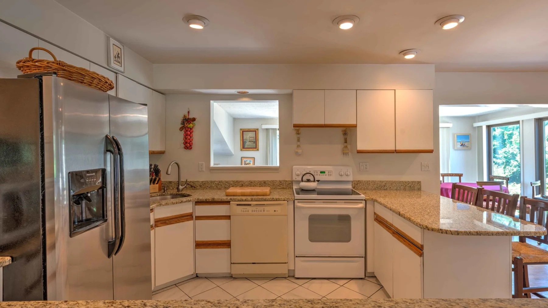 A kitchen with stainless steel appliances and a counter opening to a dining area.