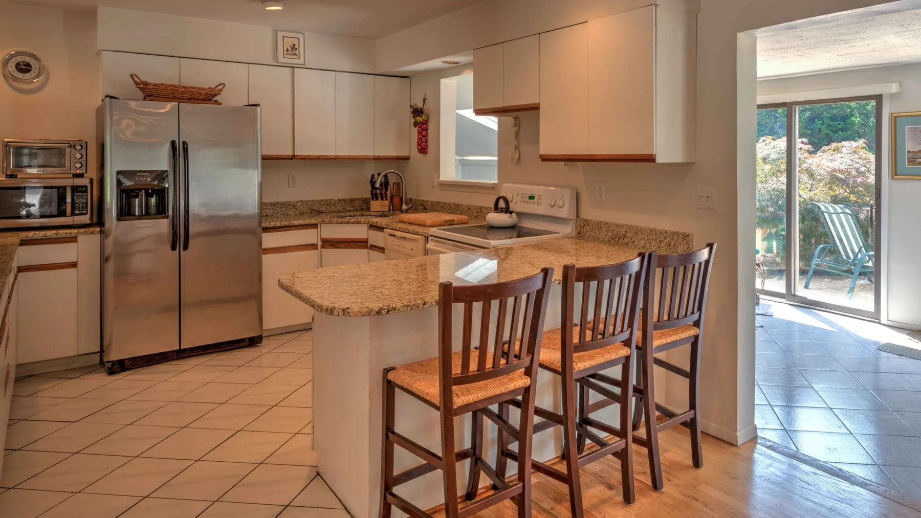 A kitchen with a granite island and adjoining sliding glass doors.