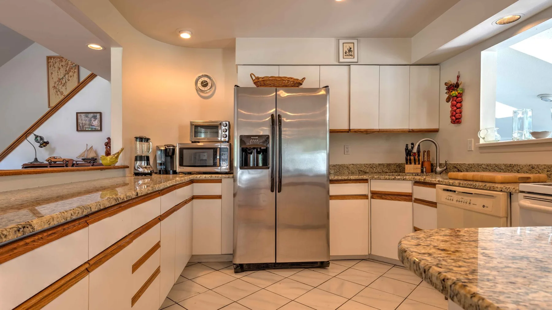 A kitchen with a stainless steel refrigerator and patterned countertops.