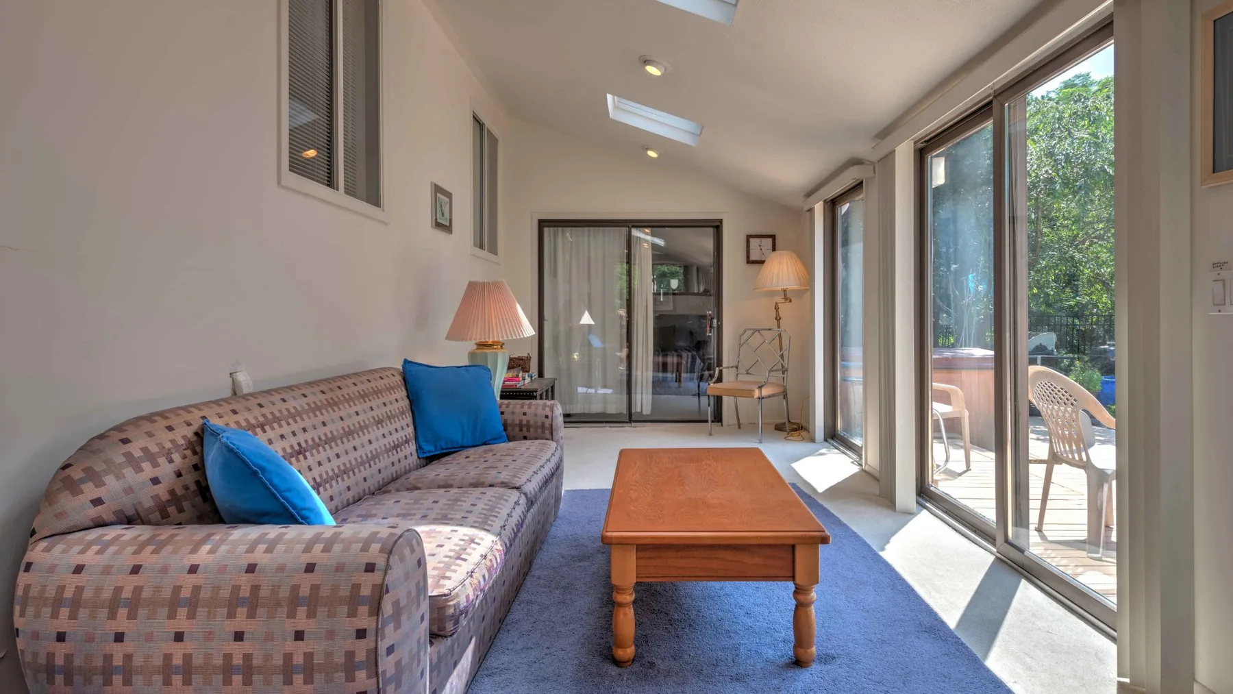 A bright living room with a patterned sofa, coffee table, and large glass doors.