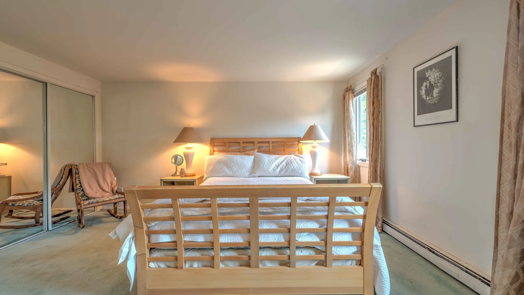 A bedroom with a bed, wooden bench, and mirrored closet doors.