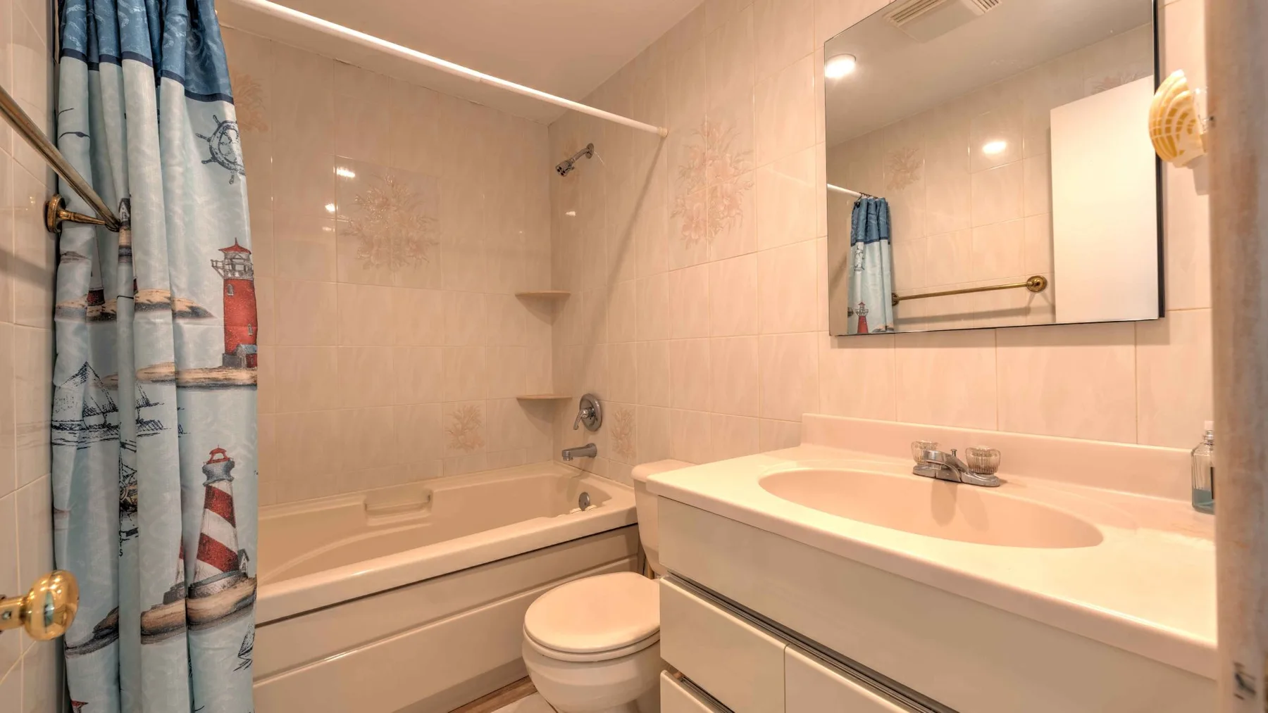 A bathroom with a bathtub, shower curtain, toilet, and sink.