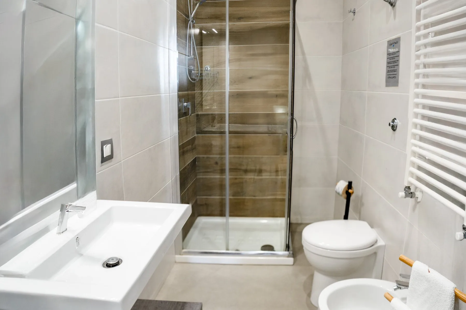 Un baño alicatado con ducha de vidrio, lavabo e inodoro.