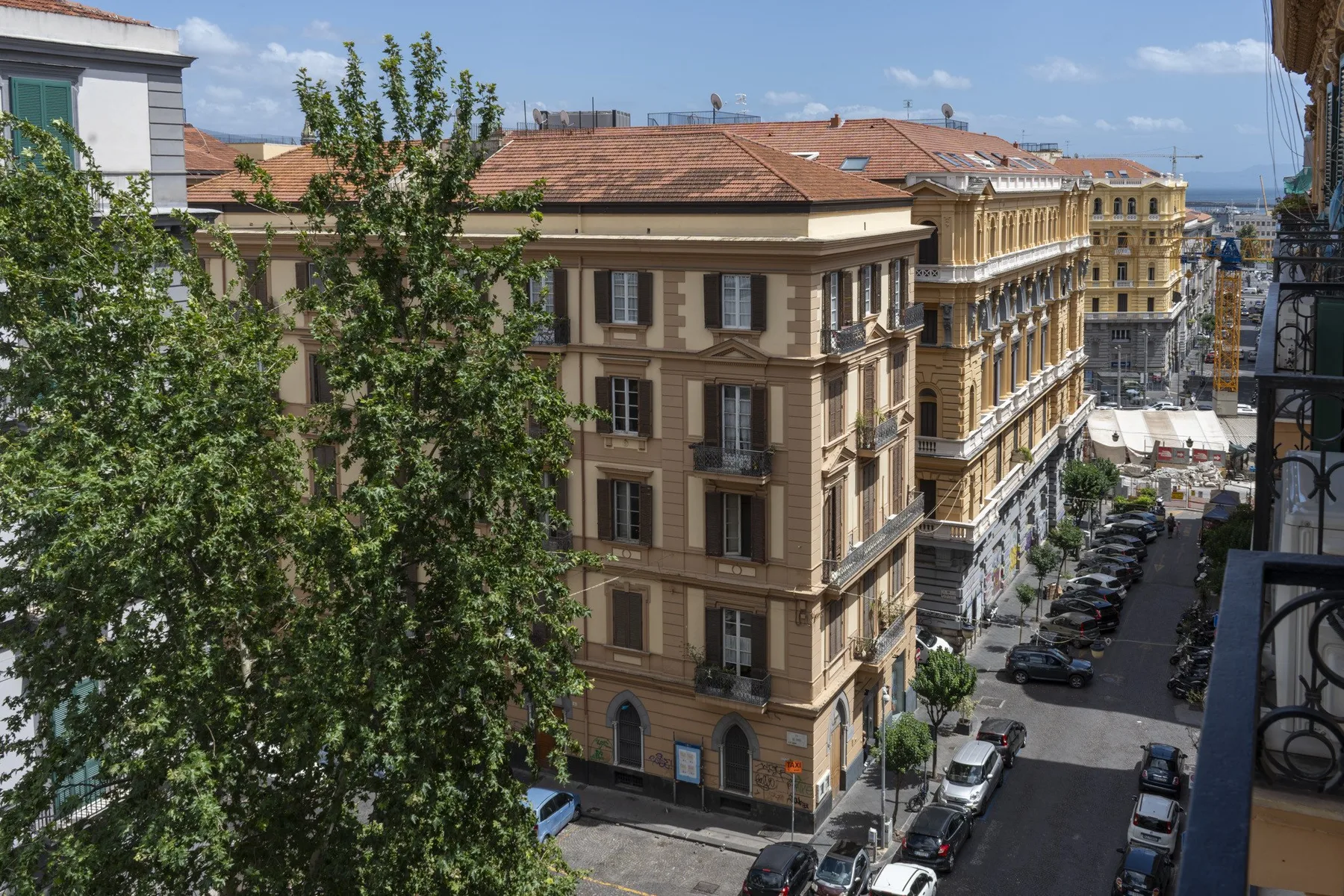 Una calle urbana pasa entre edificios de varias plantas, con coches estacionados.
