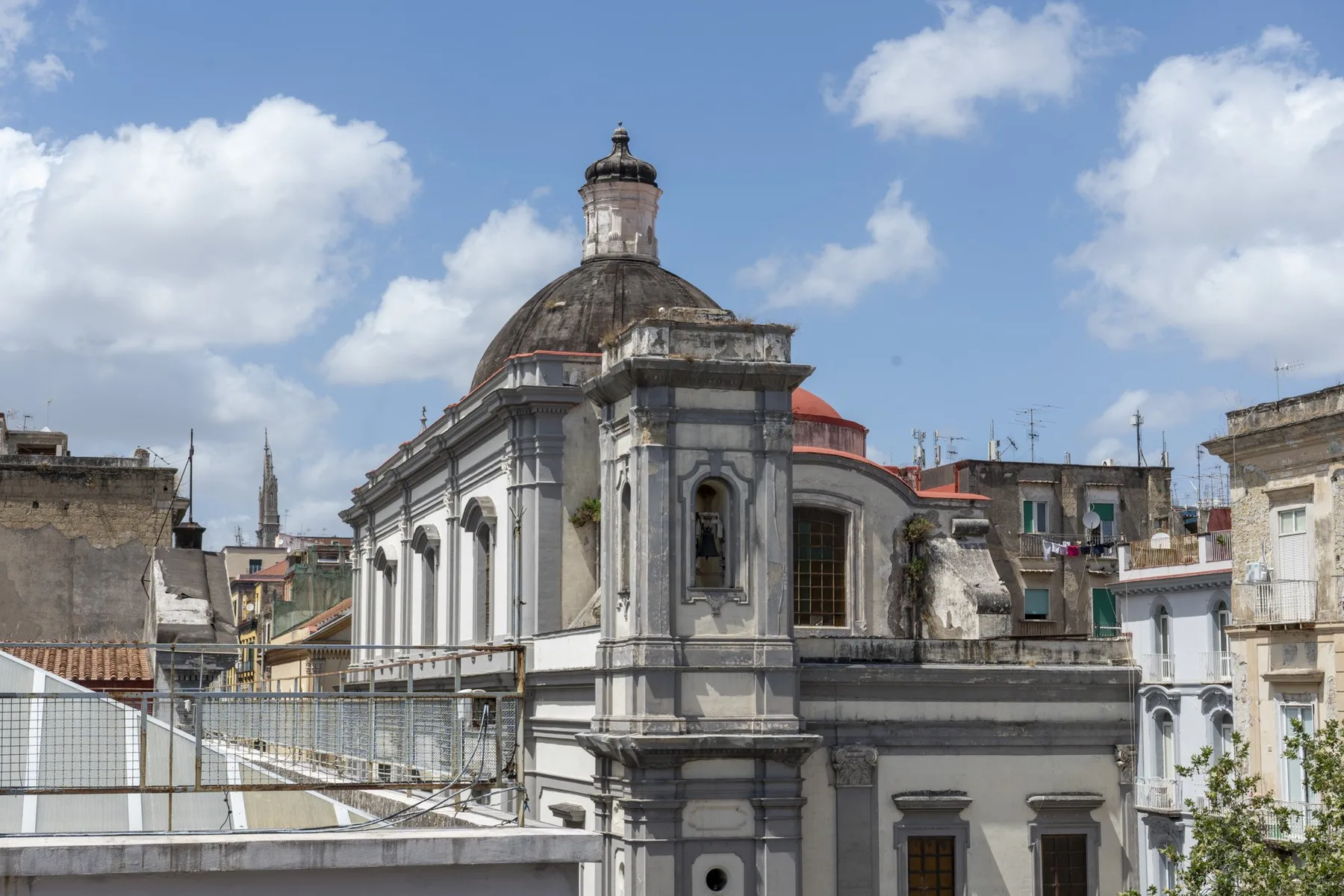 Un edificio histórico ornamentado con techo abovedado se alza entre edificios cercanos de la ciudad.