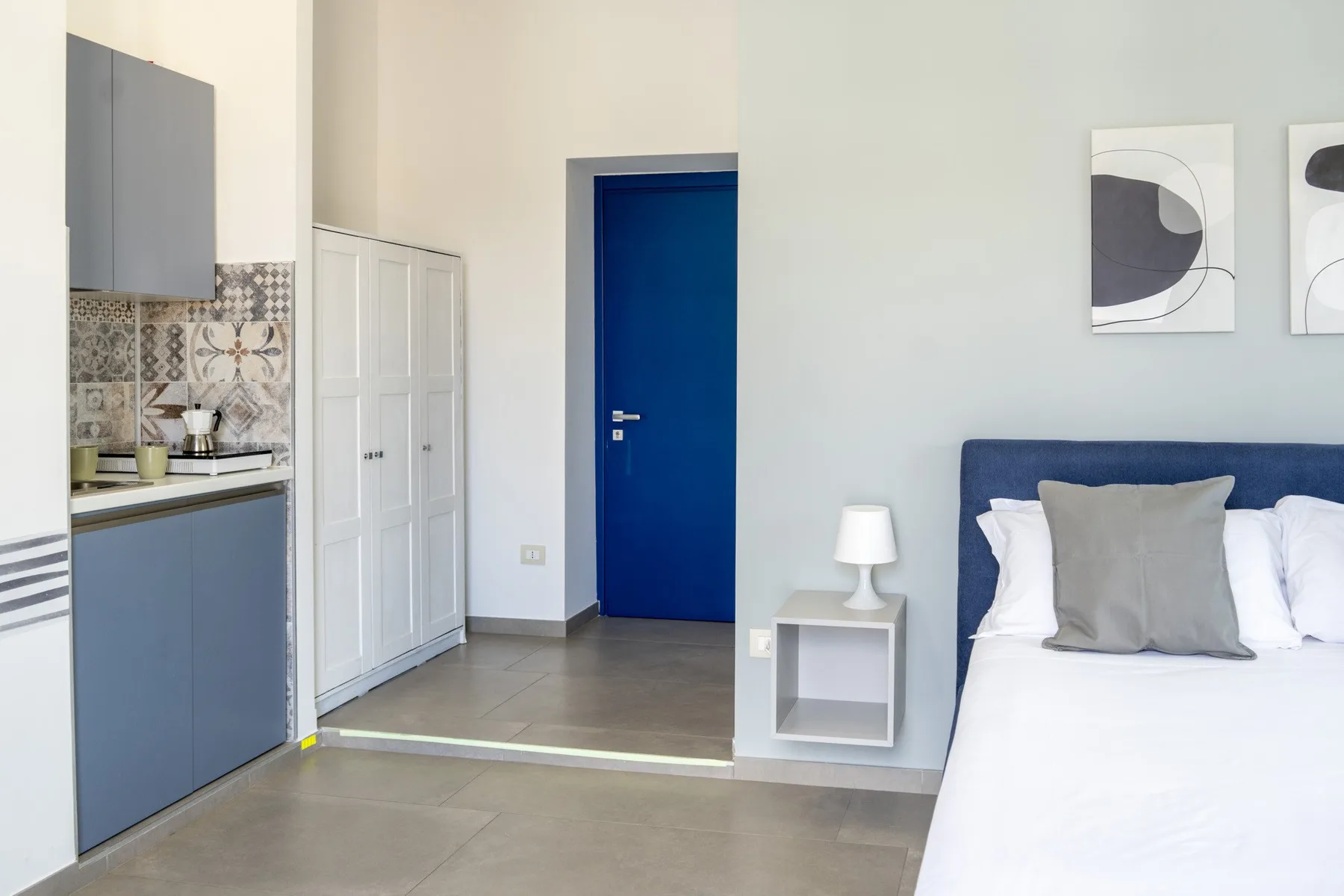 Un dormitorio con una cama junto a una puerta azul y armarios empotrados.