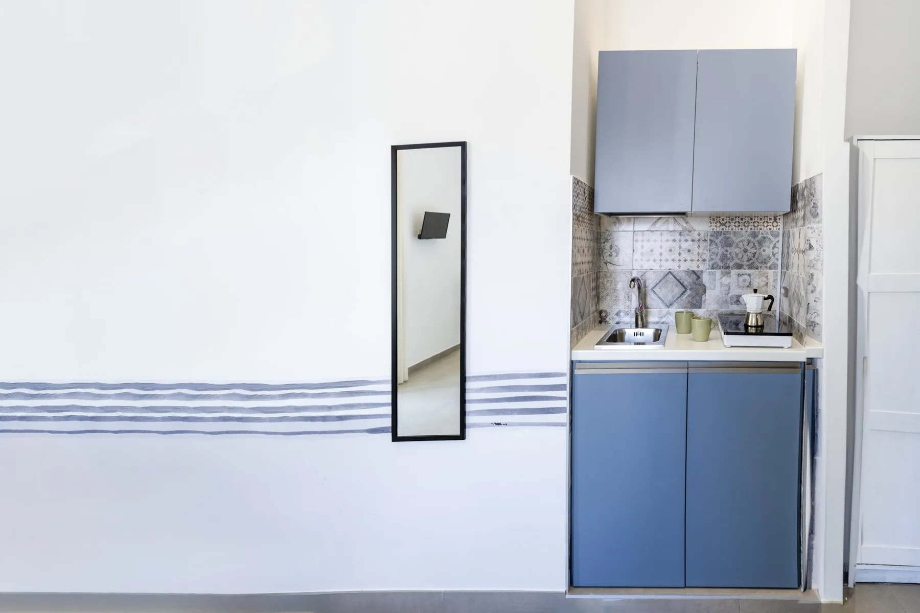 Una pequeña cocina con gabinetes azules y un salpicadero estampado.