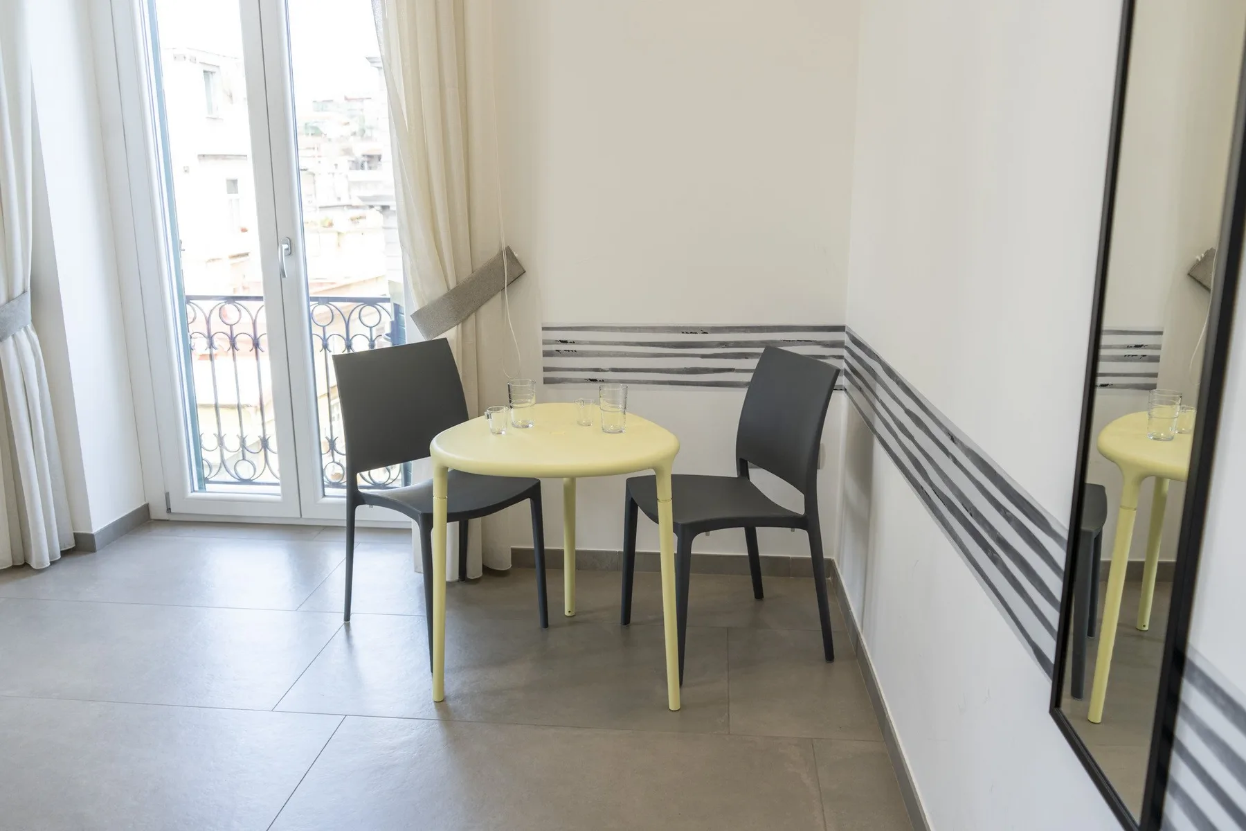Una pequeña zona de comedor con una mesa redonda y dos sillas junto a una ventana.
