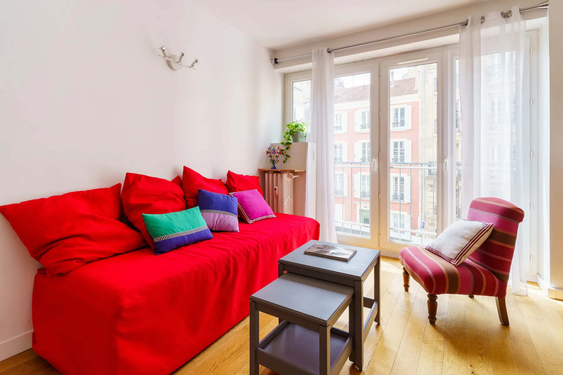A bright living room with a red sofa and large windows.