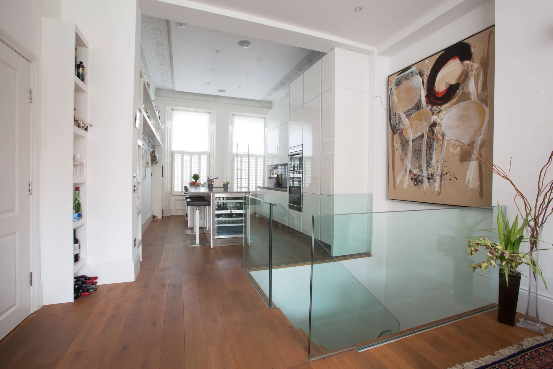 Una cocina moderna y luminosa con una barandilla de vidrio y ventanas grandes.