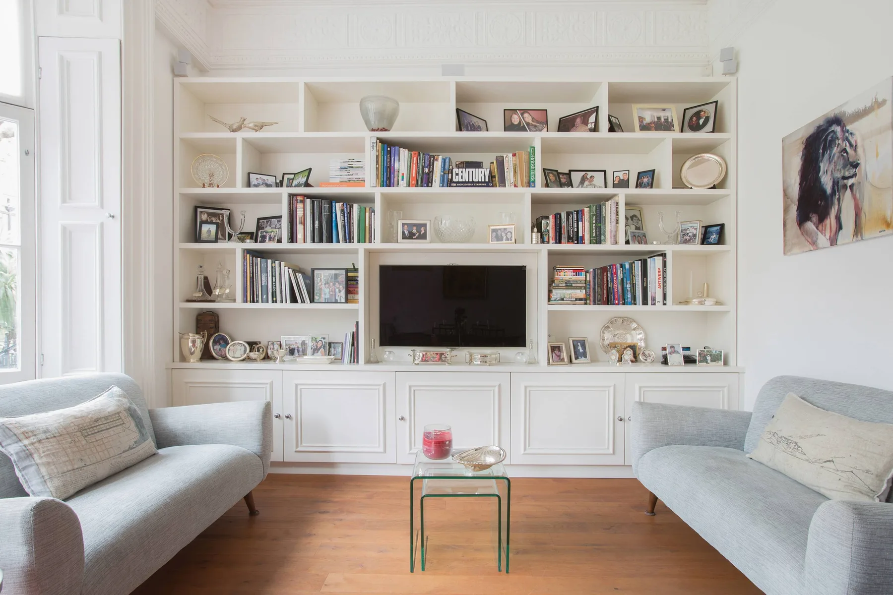 Una sala luminosa con estanterías empotradas y asientos alrededor de un televisor.