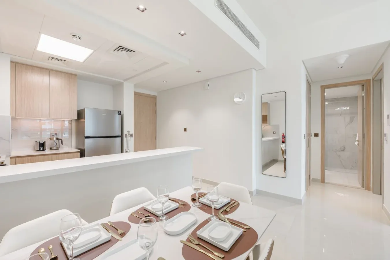 Un comedor luminoso con la mesa puesta junto a una cocina abierta.