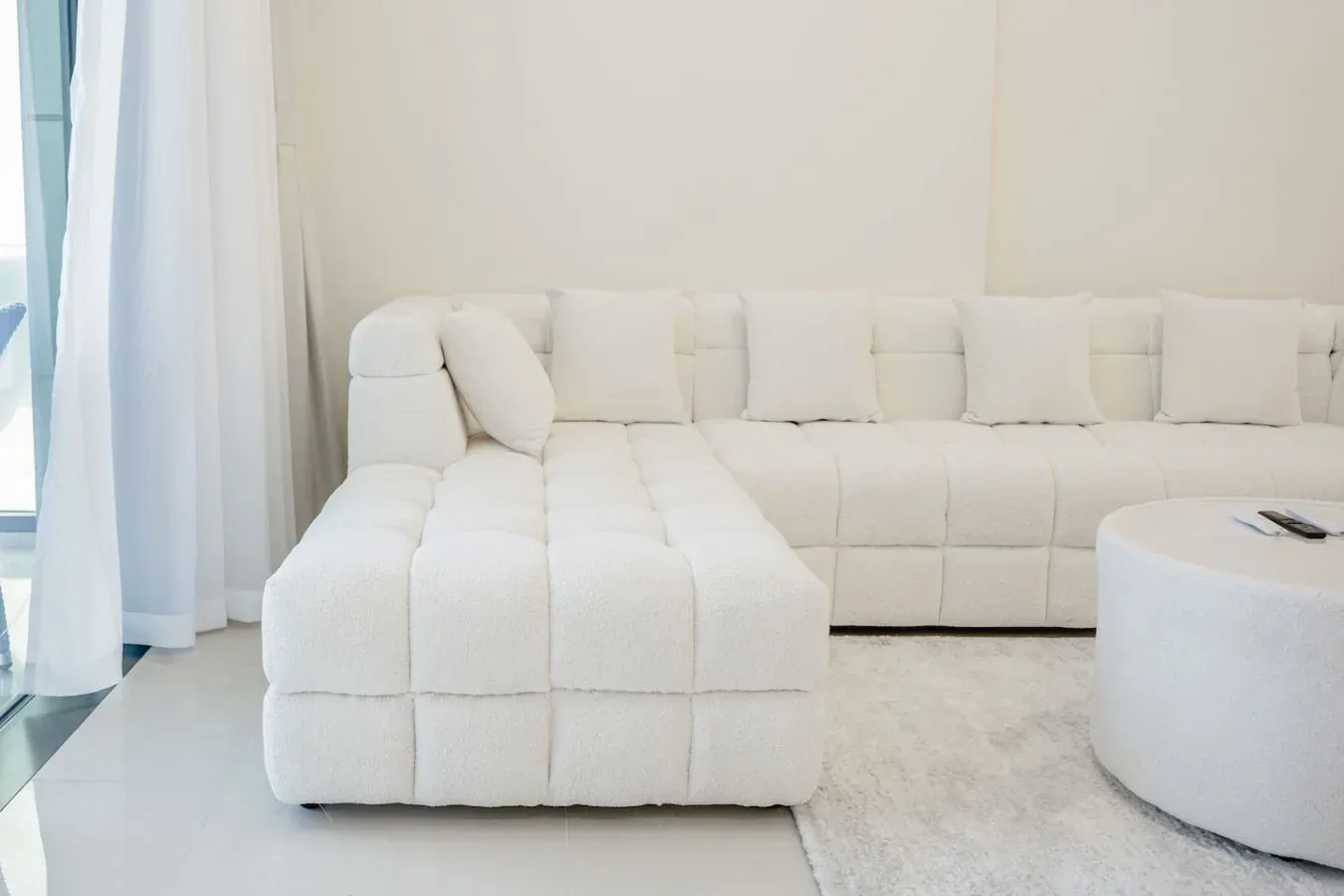 Una sala luminosa con asientos seccionales blancos junto a una ventana grande.