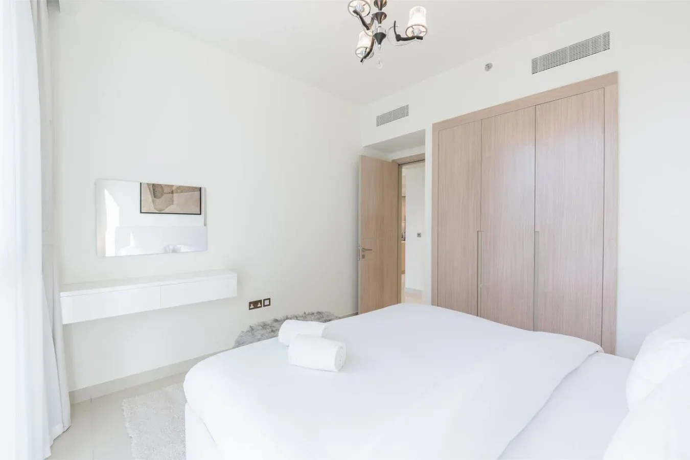 Un dormitorio luminoso con una cama bien arreglada y armarios empotrados.