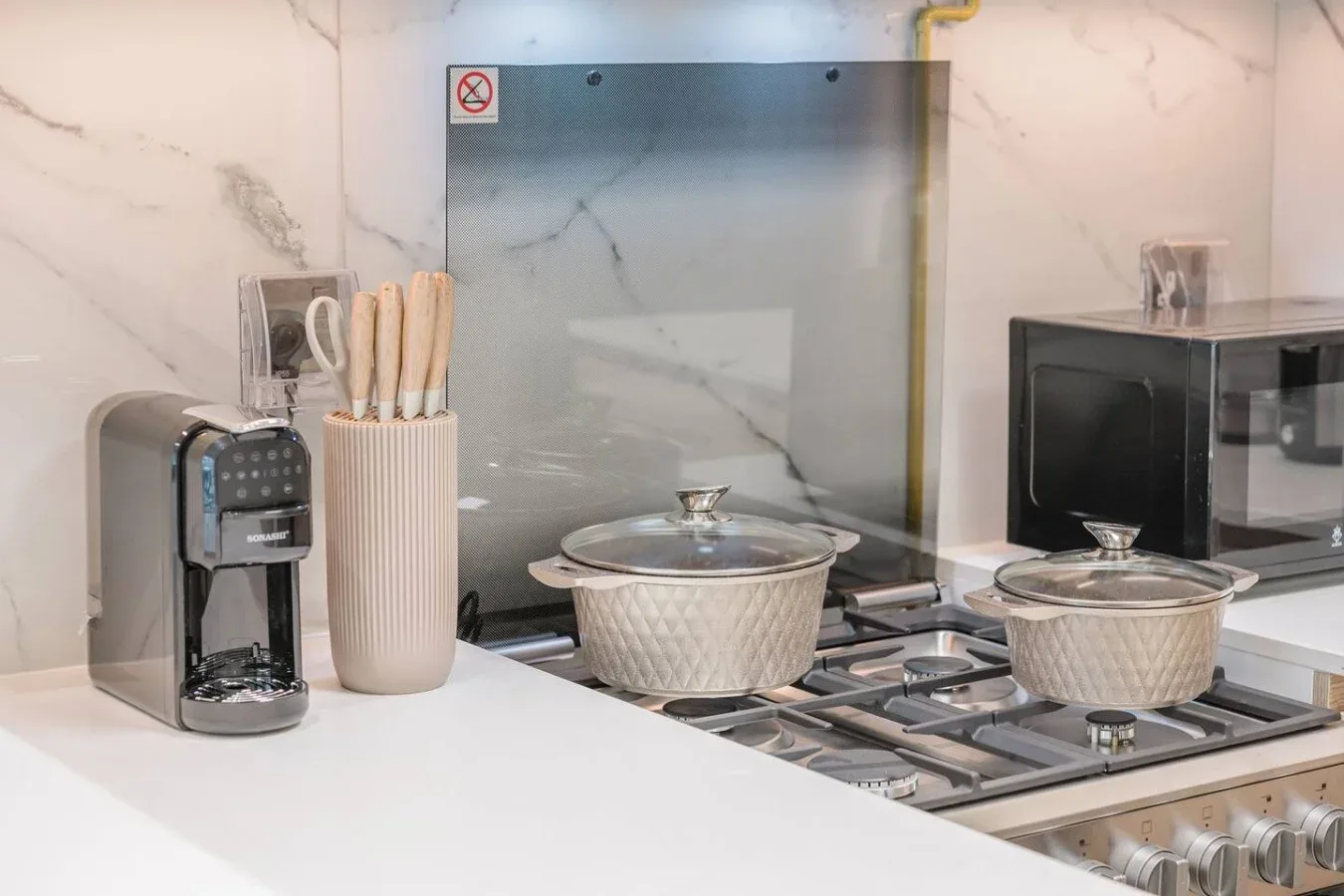Una cocina con ollas sobre la estufa y una cafetera en la encimera.