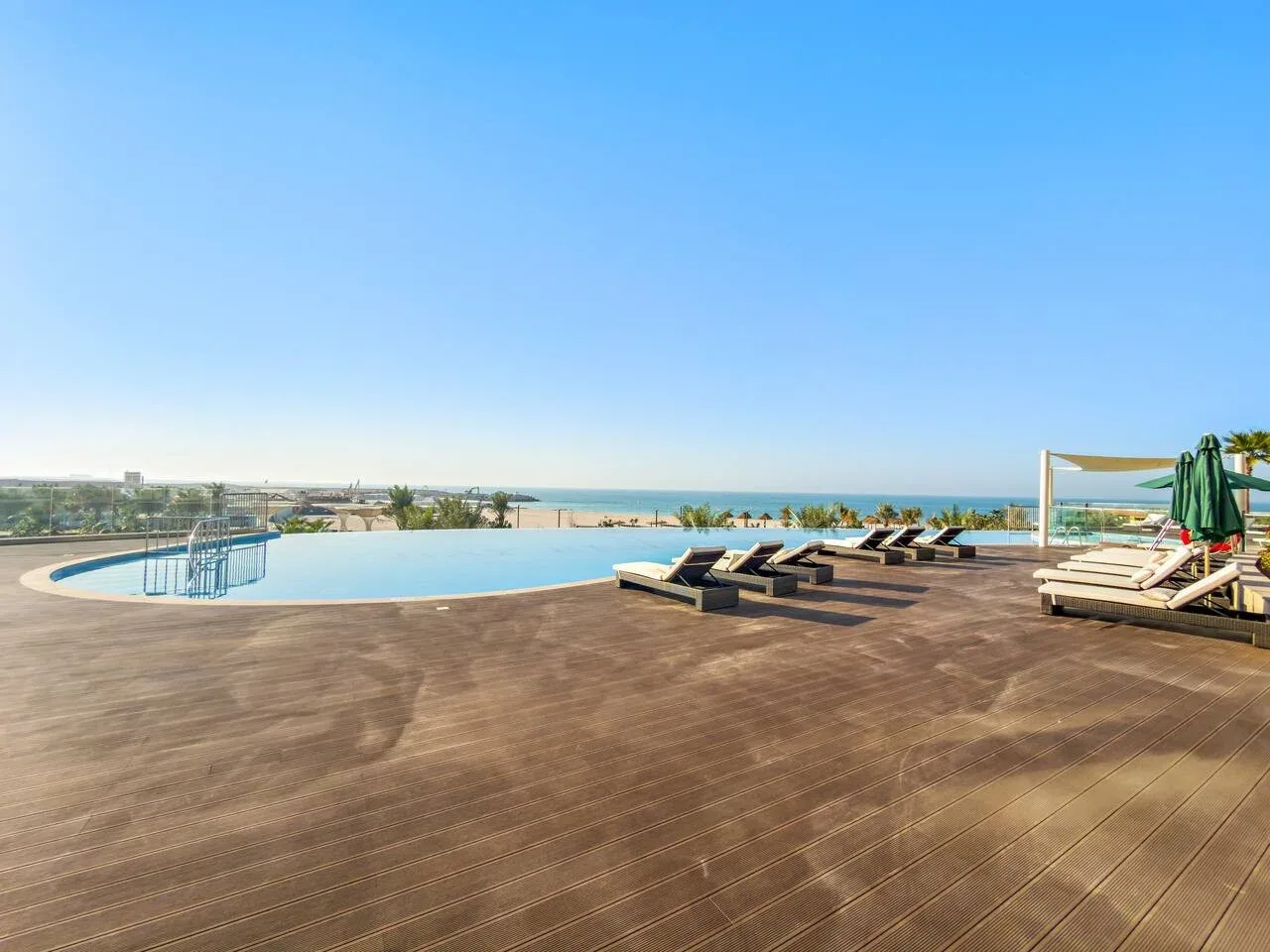 Una terraza con piscina ofrece vistas al mar y tumbonas junto al agua.