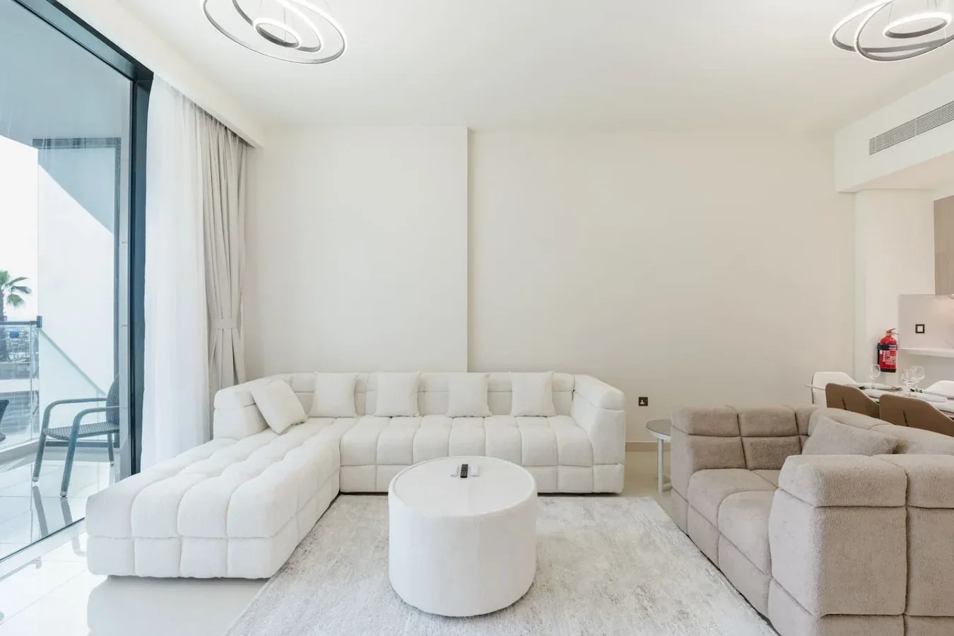 Una sala luminosa con asientos claros y una mesa de centro redonda.