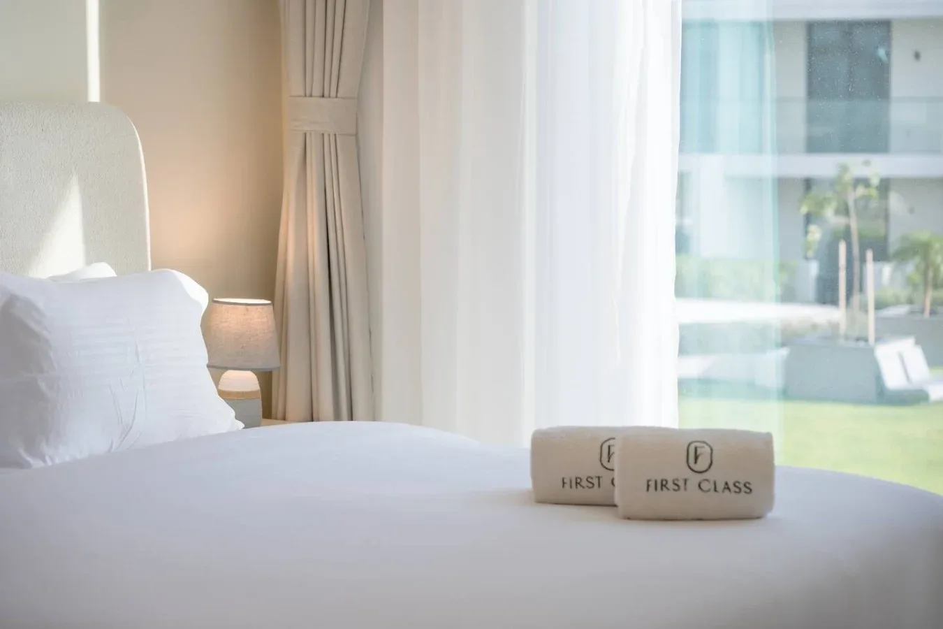 Un dormitorio luminoso con una cama bien tendida junto a una ventana grande.
