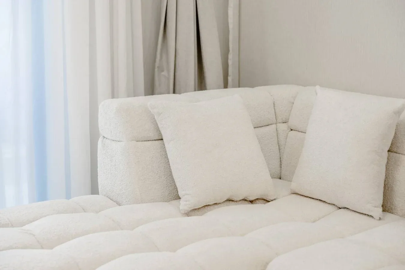 Una zona de asiento clara con cojines junto a cortinas.