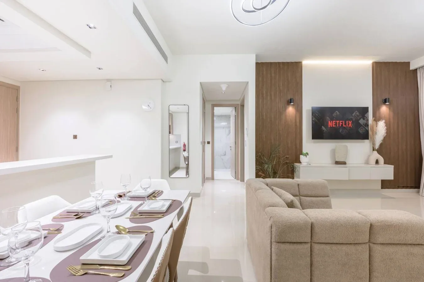 Una moderna sala de estar y comedor con la mesa puesta y un televisor.