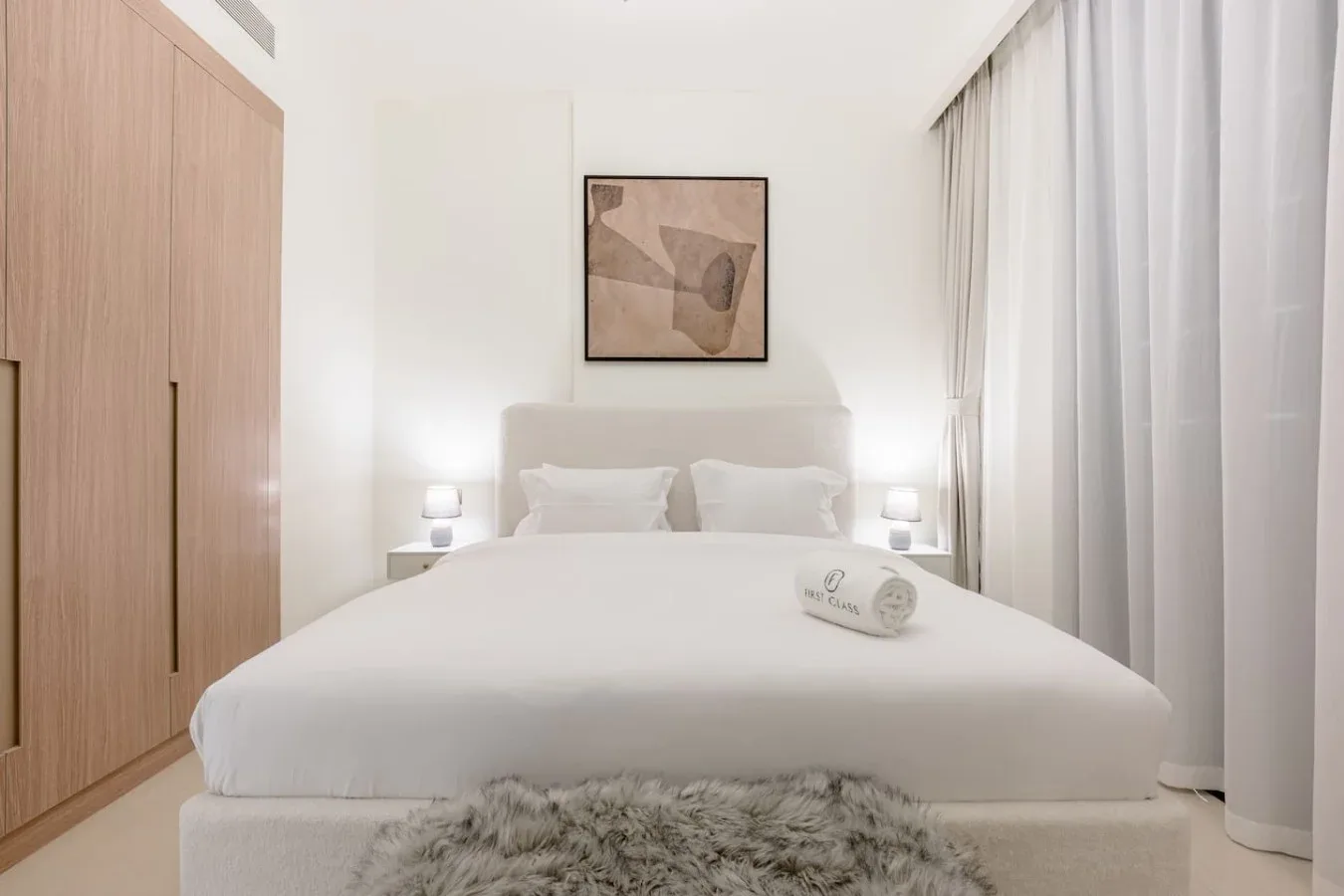 Un dormitorio luminoso con una cama bien tendida y cortinas hasta el suelo.