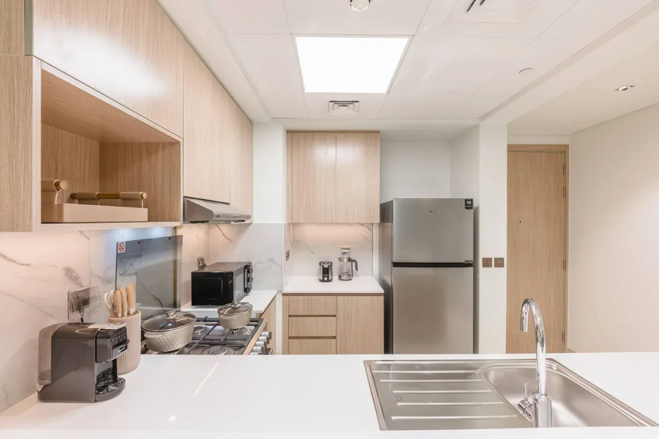 Una cocina moderna con gabinetes claros, un refrigerador de acero inoxidable y un fregadero.