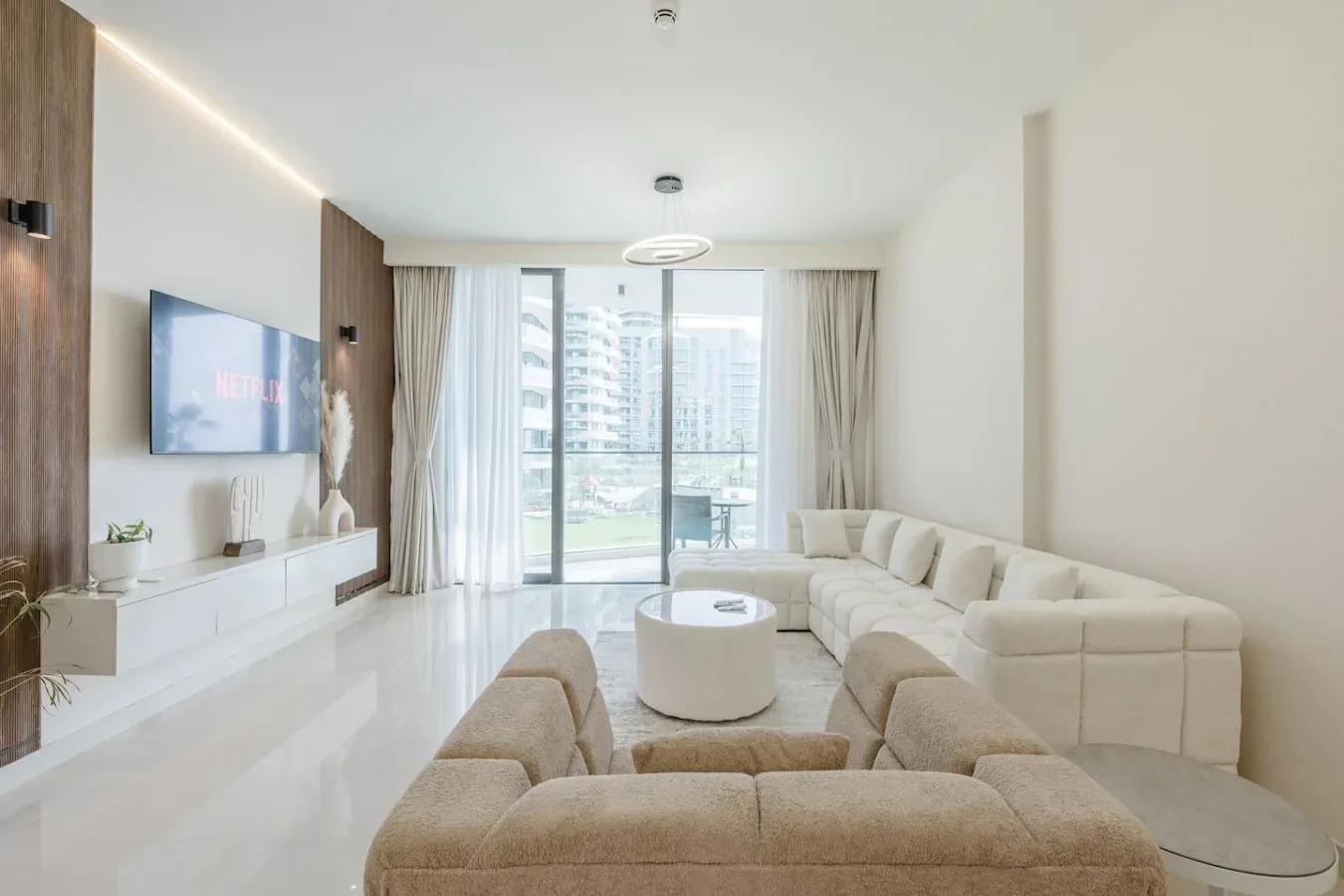 Sala de estar con asientos alrededor de una mesa de centro y grandes ventanales.