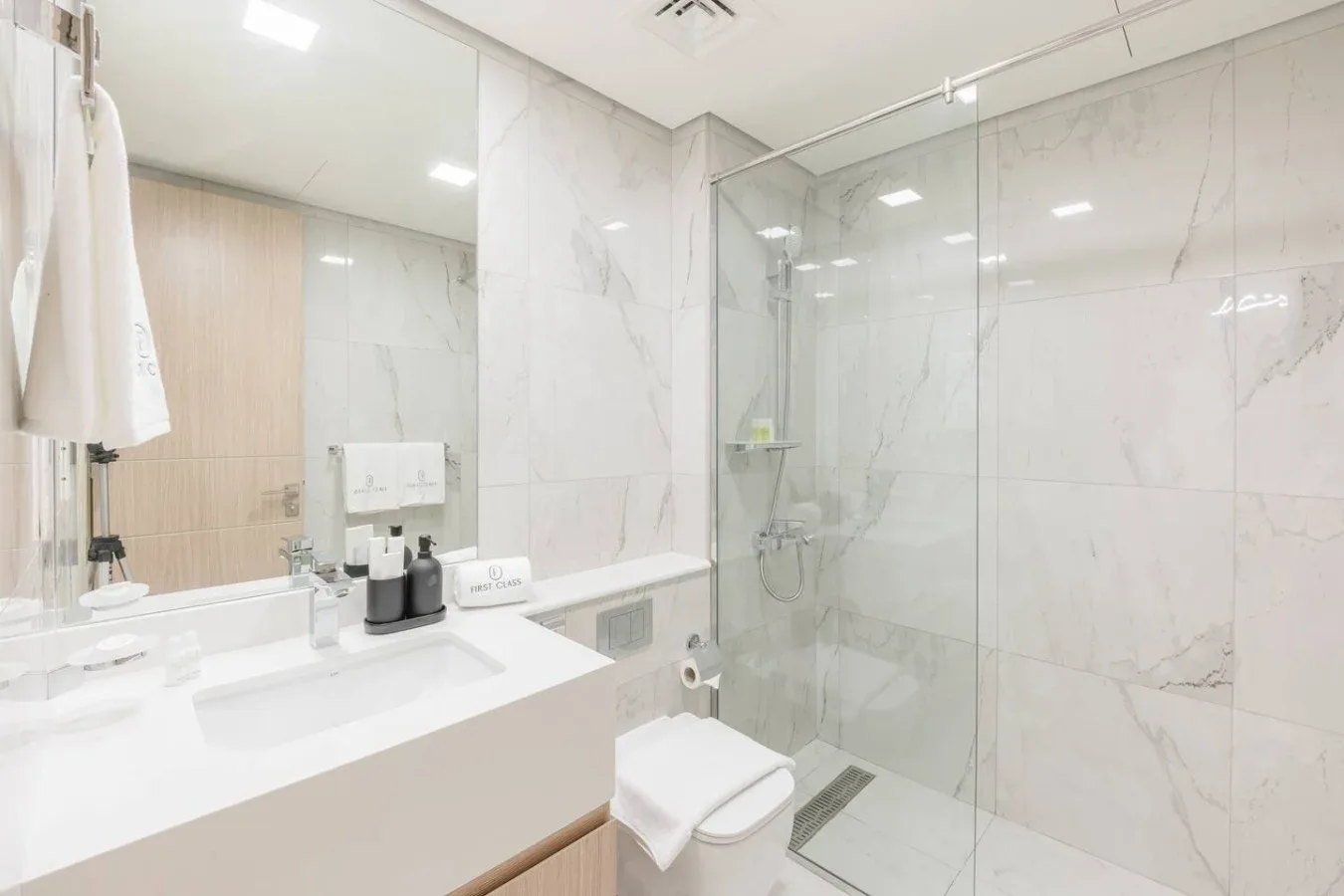 Un baño luminoso con lavabo, inodoro y ducha de cristal.