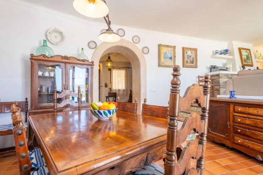 Un comedor con una gran mesa de madera y un aparador con puertas de vidrio.