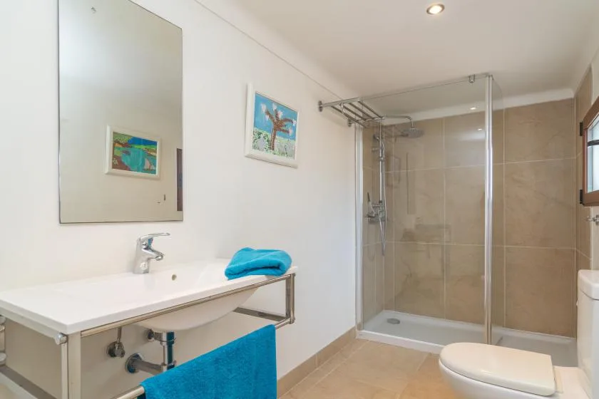 Un baño luminoso con lavabo, inodoro y ducha con azulejos.
