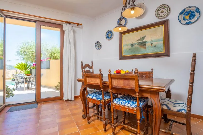 Comedor con mesa y sillas de madera junto a puertas correderas de cristal.