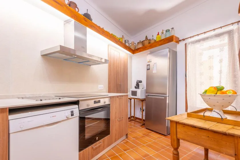 Una cocina luminosa con estufa, refrigerador y mesa de madera.