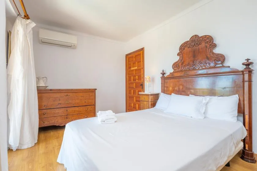 Un dormitorio con una cama grande, un cabecero de madera tallada y una cómoda de madera.