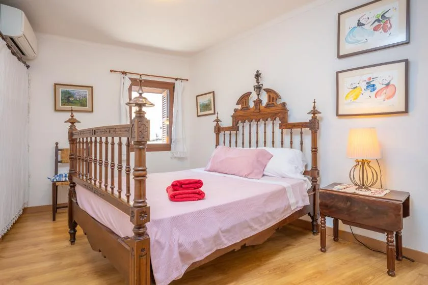 Un dormitorio con una cama de madera tallada, ropa de cama rosa y cuadros enmarcados.
