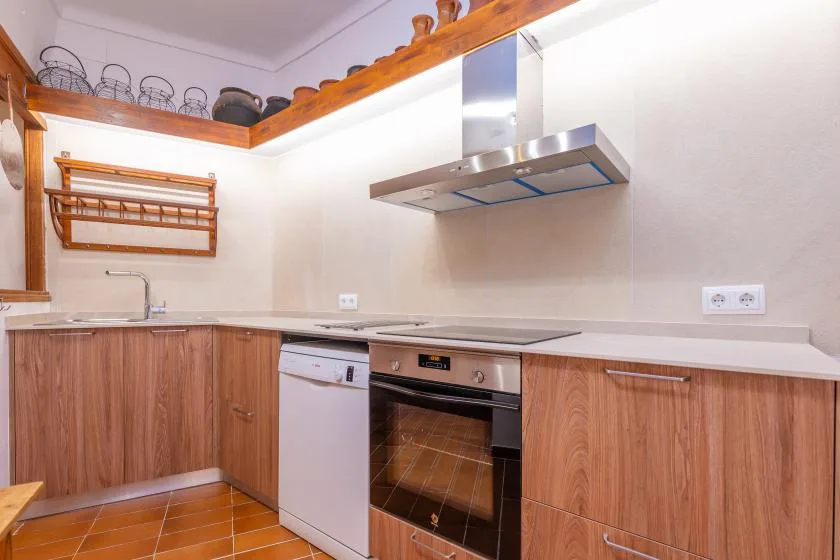 Una cocina compacta con muebles de madera, una encimera y una campana extractora de acero inoxidable.