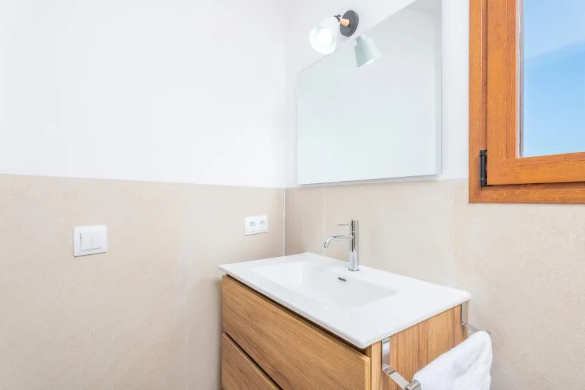Un lavabo de baño con espejo está junto a una ventana.