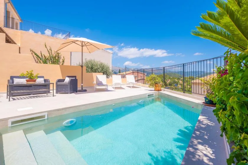 Una piscina al aire libre con asientos de descanso y una vista abierta más allá de la barandilla.