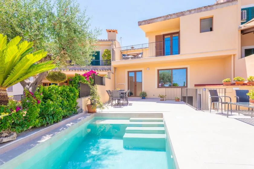 Una piscina y un patio junto a una casa de dos plantas.