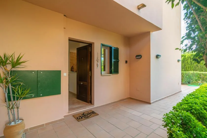 A covered entrance patio with a doorway, window, and tiled floor.