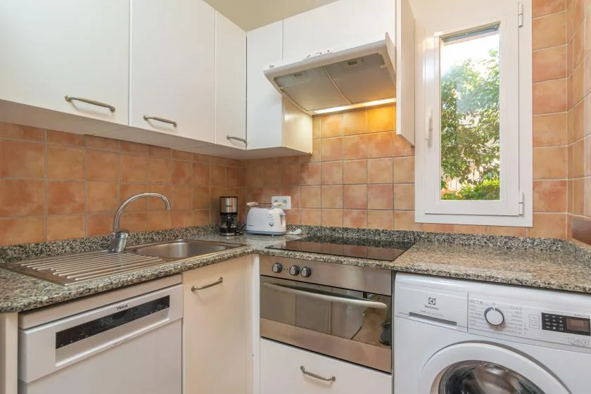 A kitchen with white cabinets, a tiled backsplash, and a window.