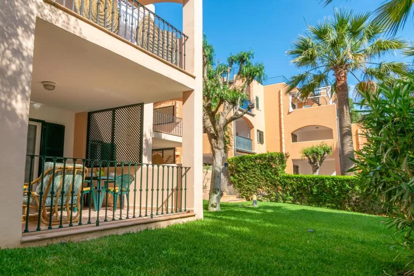 Edificios de apartamentos con balcones dan a un patio verde con palmeras.