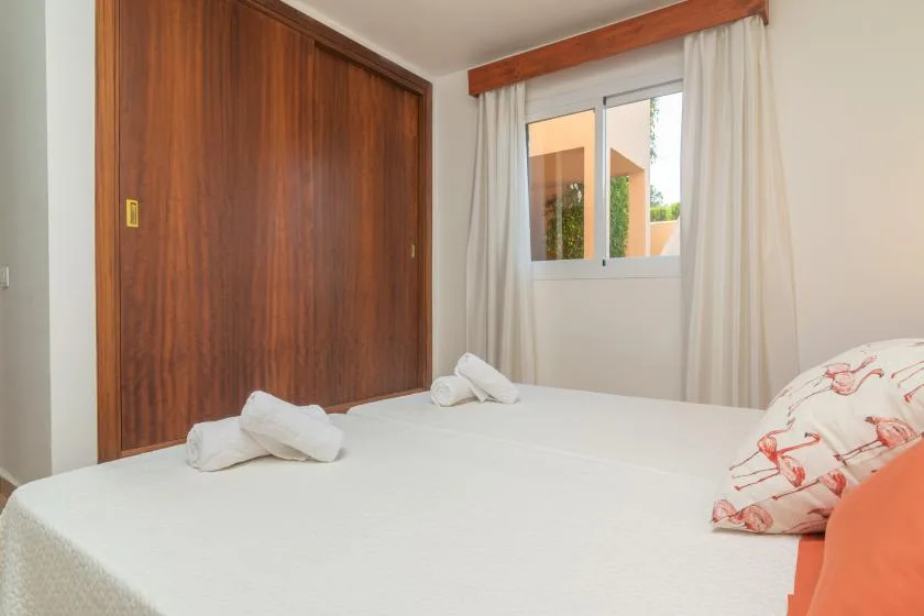 A bedroom with a neatly made bed and a window framed by curtains.