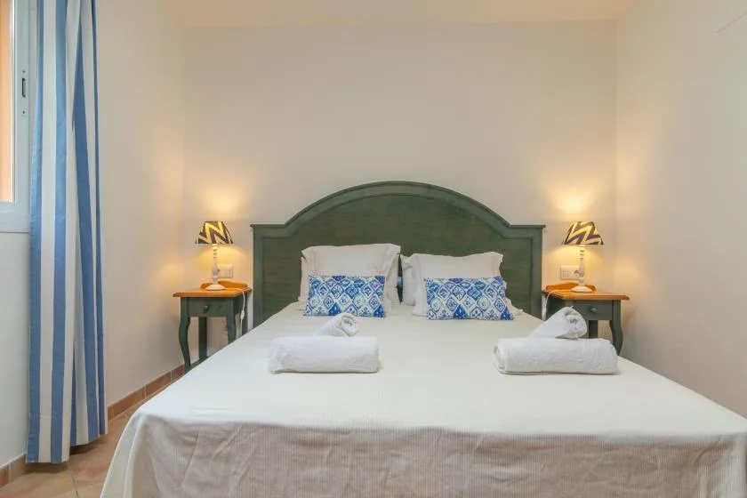A bedroom with a neatly made bed, patterned pillows, and matching bedside tables.